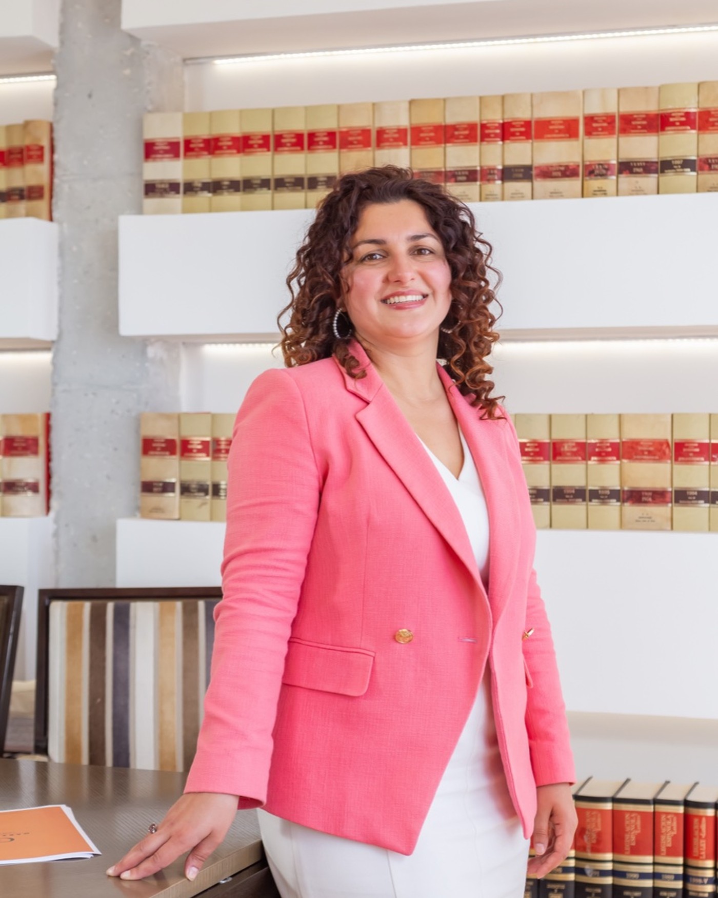 Retrato de Guzel Zamaltdinova en el despacho, apoyada en la mesa de reuniones ante las estanterías de repertorios.