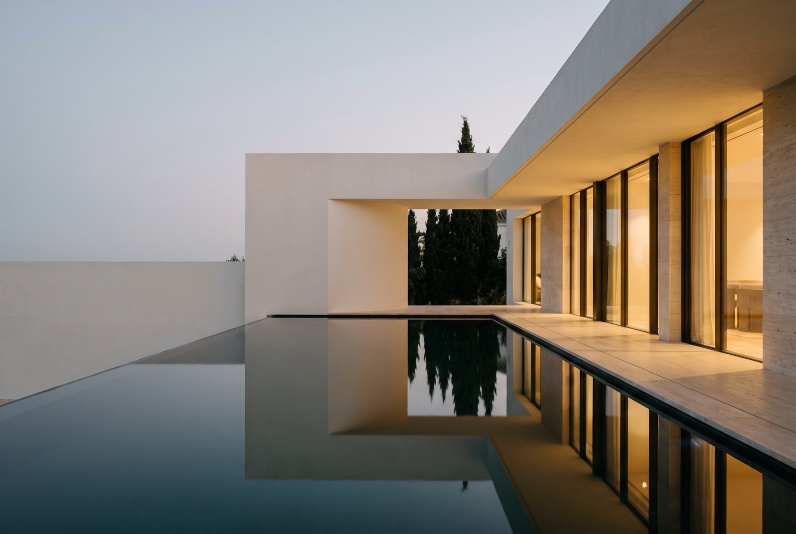 Villa contemporánea de Marbella reflejada en la piscina desbordante al anochecer