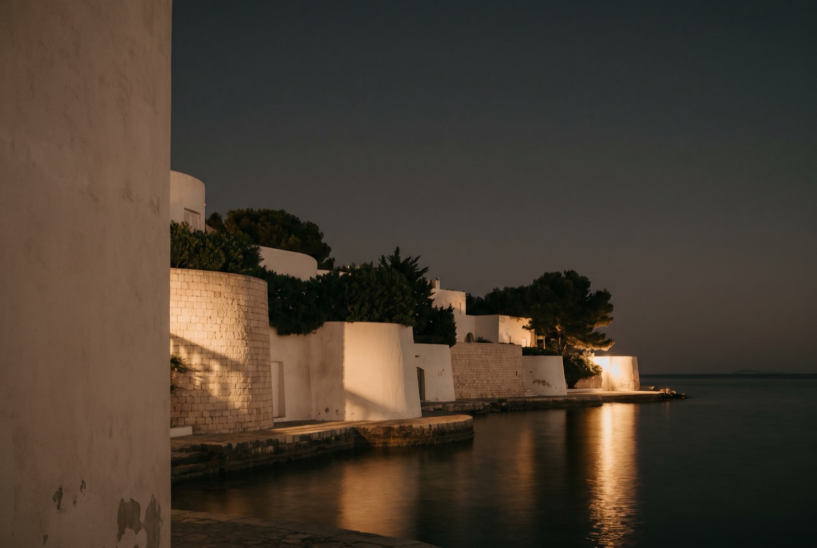 The boulevard in San Pedro Alcántara, Marbella, at dusk: a woman walks home from work beneath the newly lit street lamps, with the last light on Sierra Blanca