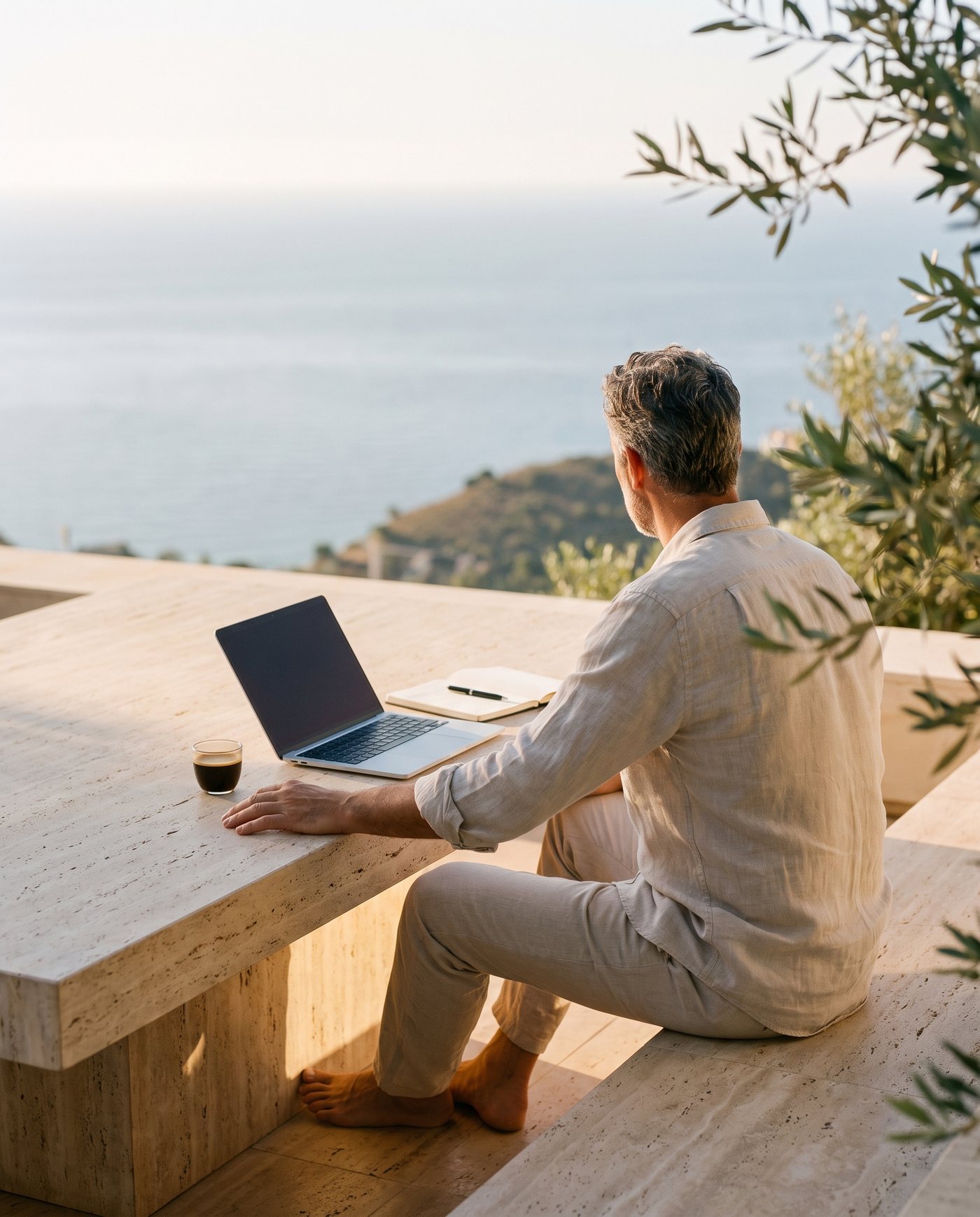 Un profesional trabajando desde la terraza de una villa mediterránea sobre el mar
